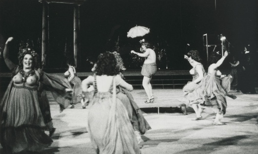 Εθνικό Θέατρο, "Θεσμοφοριάζουσες" (1989). Αριστερά: Τζέση Παπουτσή (Κρίτυλλα). Στο κέντρο: Γιώργος Μιχαλακόπουλος (Μνησίλοχος) και ο Χορός. Αρχείο Εθνικού Θεάτρου. 